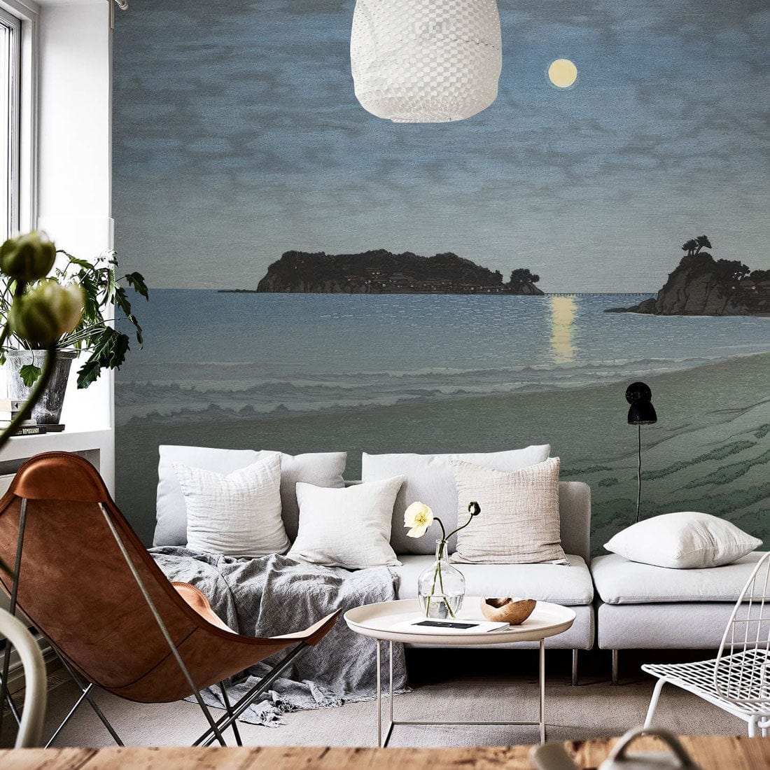 Mystical Moonlit Seascape Mural in living room; white sofa, brown chair, wooden flooring.