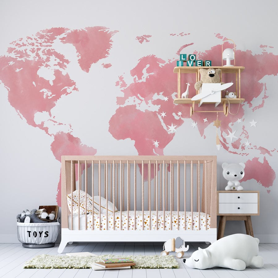 Blush Pink Watercolour World Map Mural in nursery with wooden cot, white walls, and stuffed toys.
