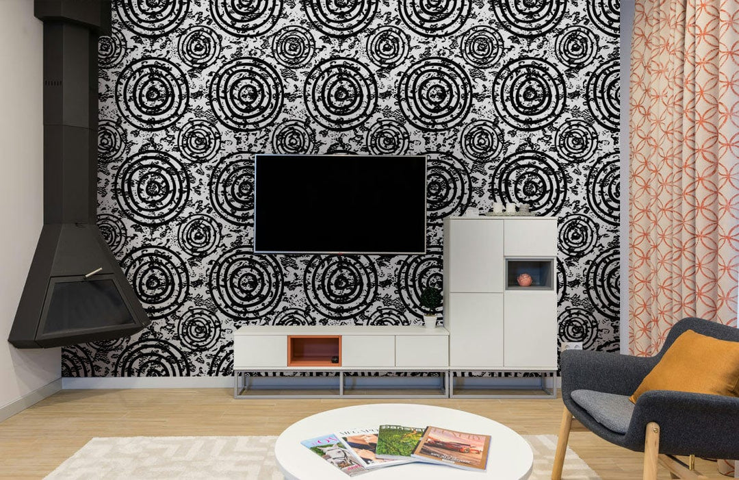 Black and white spiral circles wallpaper, stylish living room with grey chair, modern furnishings, wood flooring.