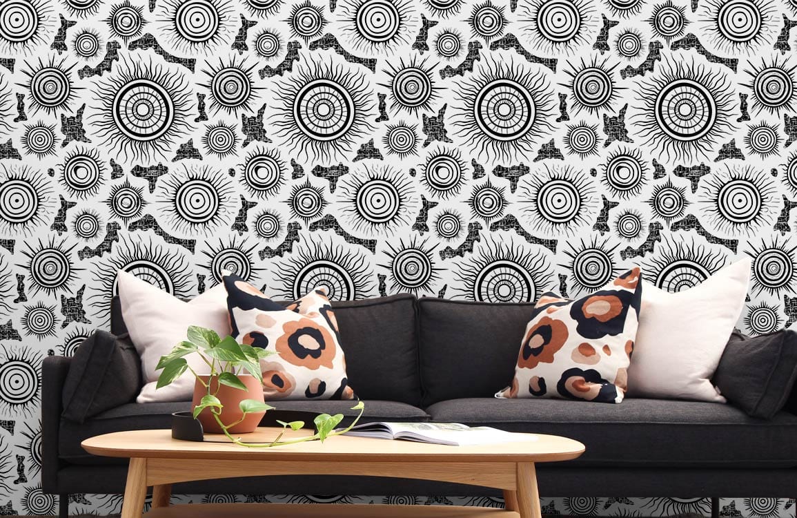Monochrome sunburst mandala wallpaper behind black sofa, wooden table in retro-styled living room.
