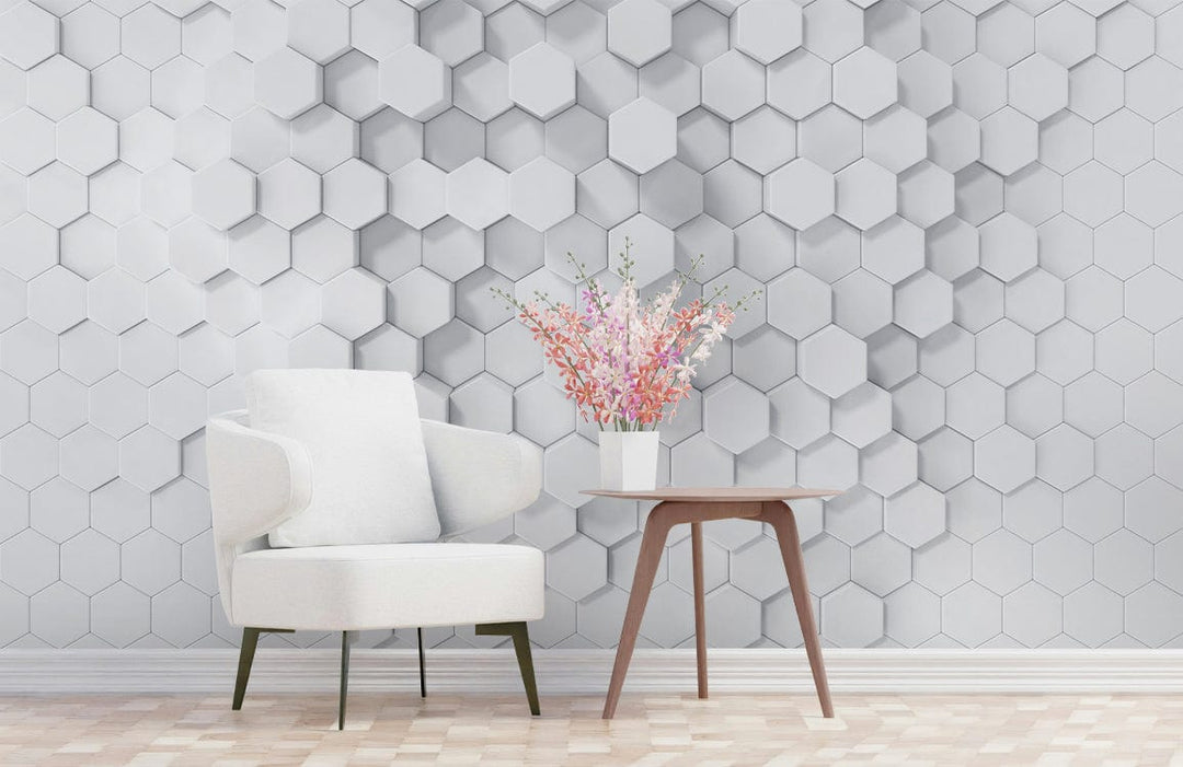 Geometric white hexagonal 3D wallpaper, minimalist design, white armchair, wooden table, laminate flooring.