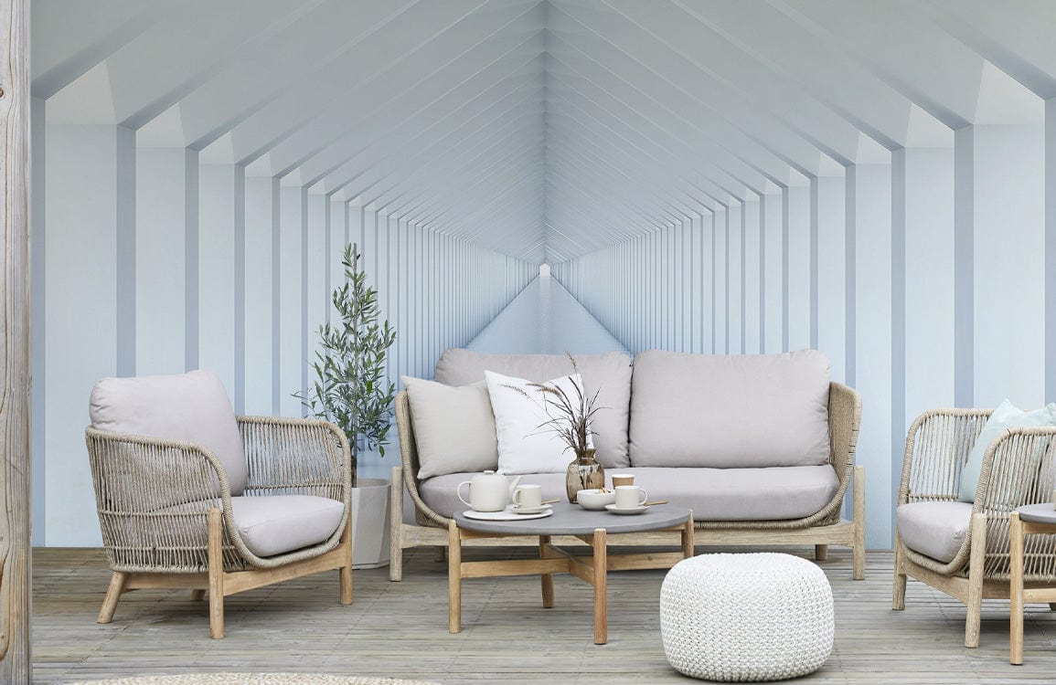 Modern white geometric mural wallpaper with beige rattan sofa, neutral tones, wooden floor, and pouffe.