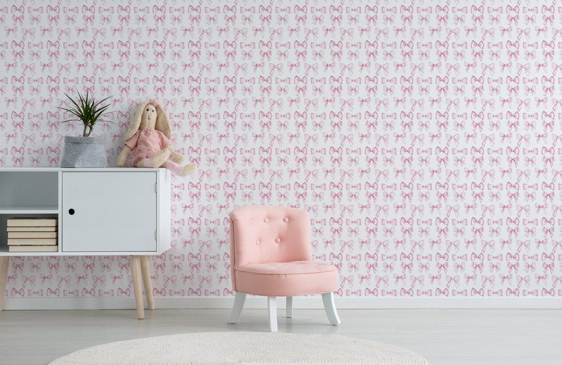 Elegant pink bow wallpaper in chic room with pastel chair, white cabinet, light wood flooring.