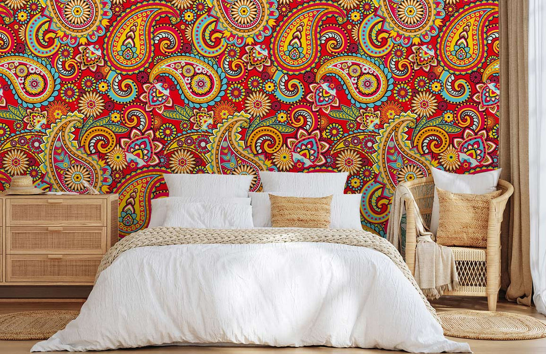 Bohemian style bedroom with vibrant paisley floral red wallpaper, wicker chairs, and wooden furniture.