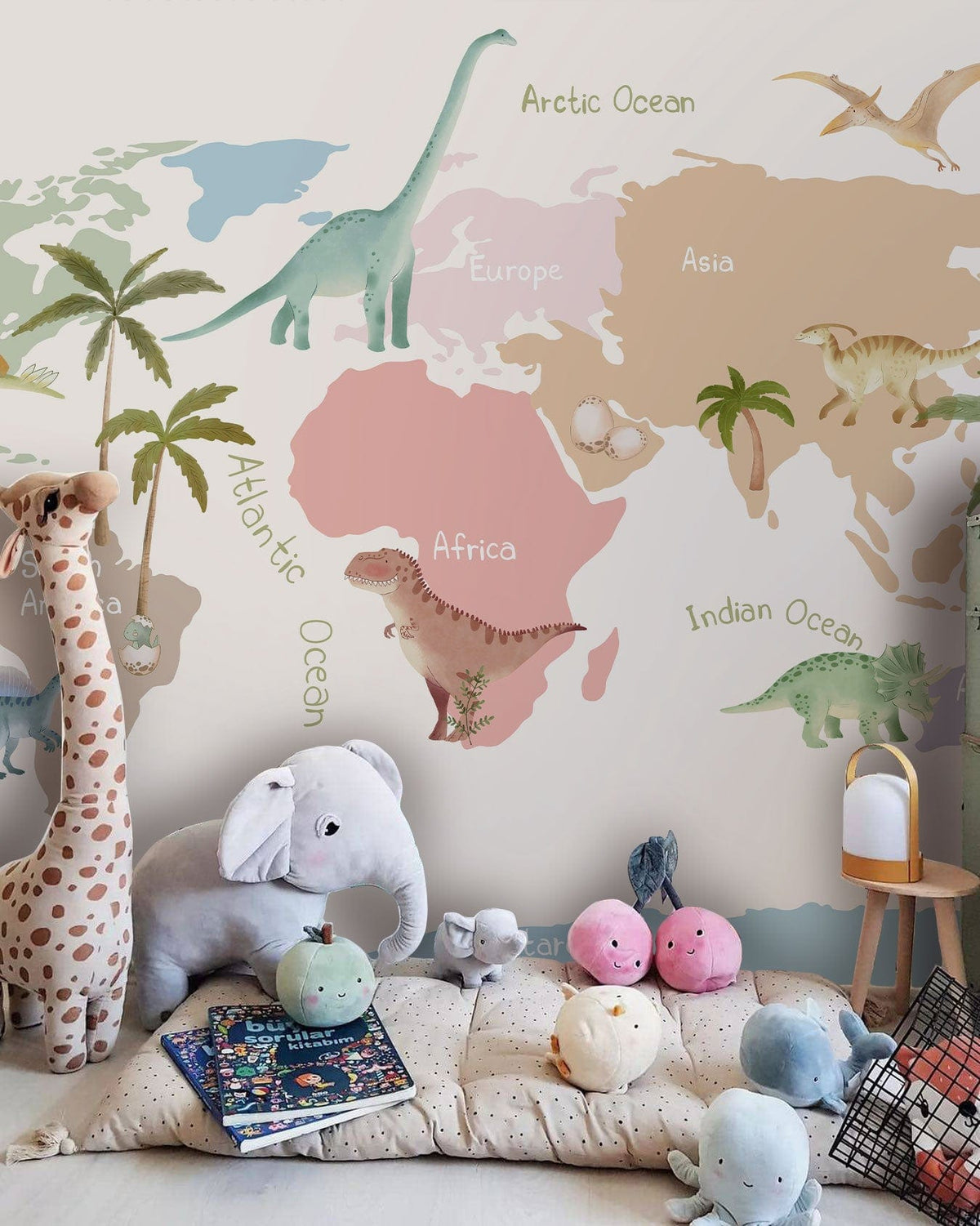 Colourful Children's Dinosaur World Map Mural Wallpaper in playful nursery with cuddly animal plush toys.