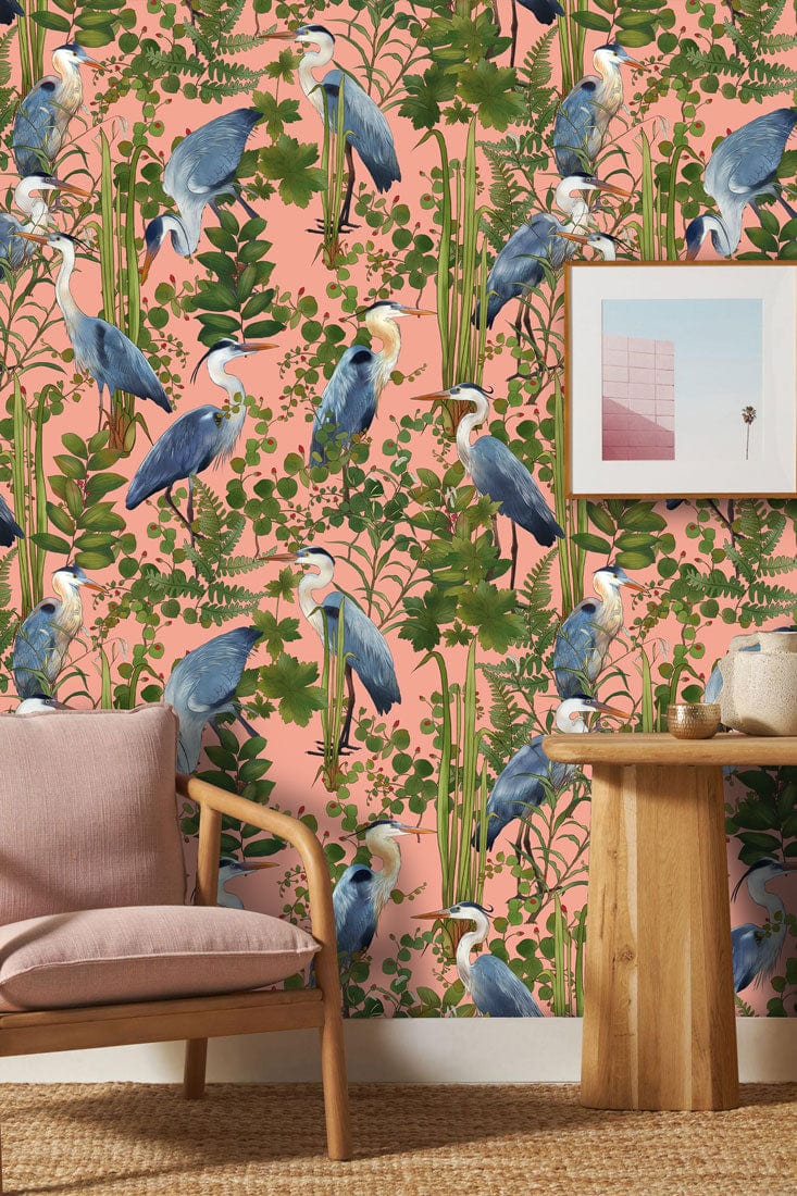 Exotic Blue Heron Botanical Mural, pink wall, wooden table, pink armchair, beige carpet, framed artwork.