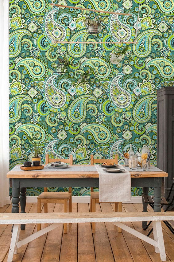 Vintage green paisley wallpaper in dining room with wooden table, chairs, bench, and hardwood flooring.