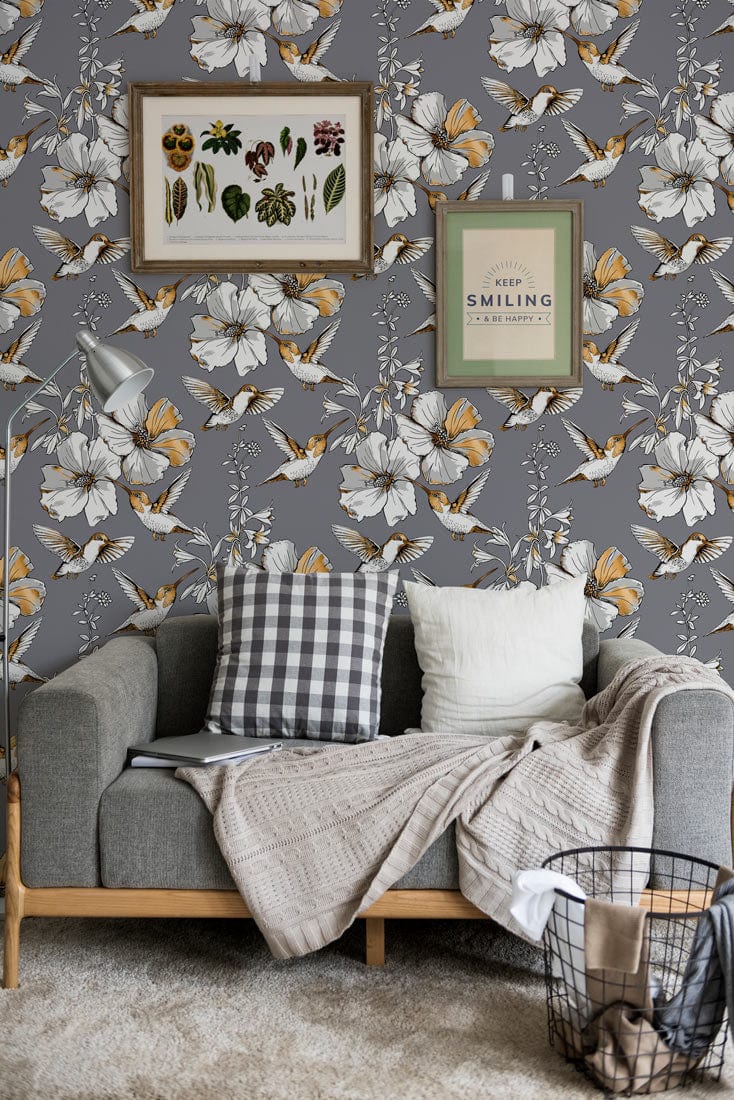 Grey floral butterfly wallpaper in living room with modern grey sofa, botanical wall art, beige rug.