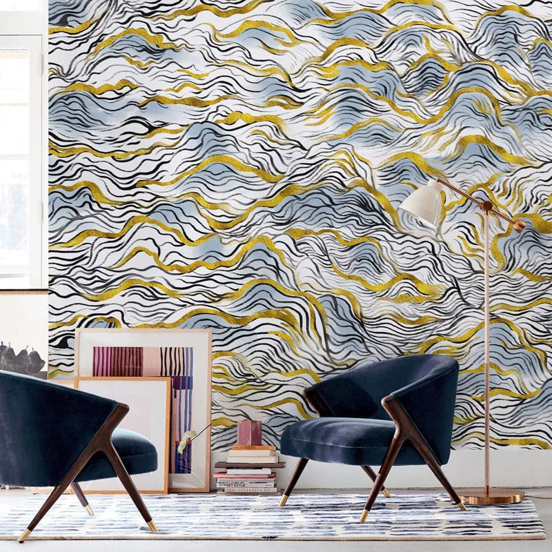 Elegant blue and gold abstract waves wallpaper in modern living room with navy chairs and artworks.