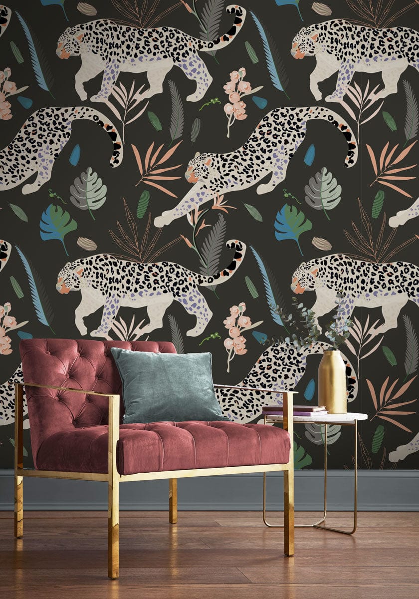 Exotic Jungle Leopard Wallpaper; colourful botanical accents, plush pink chair, round gold side table, wooden floor.