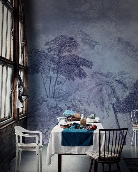 Vintage blue forest mural in dining room with eclectic chairs, wooden flooring, and large windows.