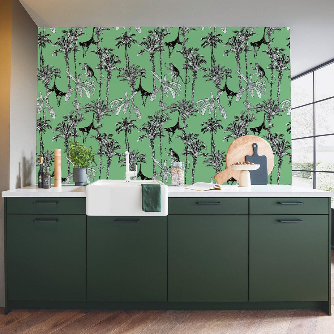 Tropical Jungle Art Deco Green Wallpaper in modern kitchen with dark green cabinets, wooden flooring.