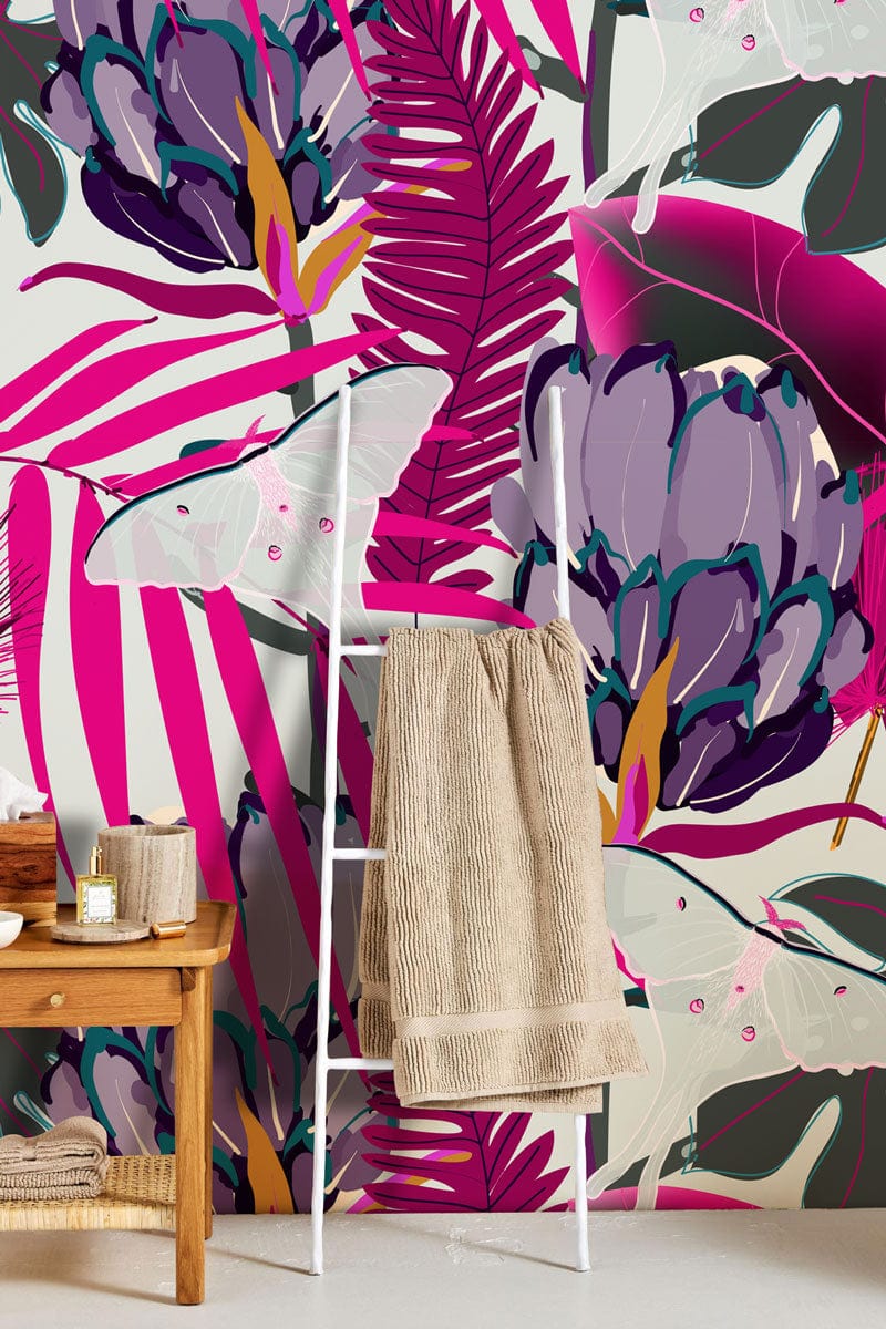 Tropical Jungle Mural Wallpaper, magenta and green leaves, towel ladder, beige rug, wooden table.