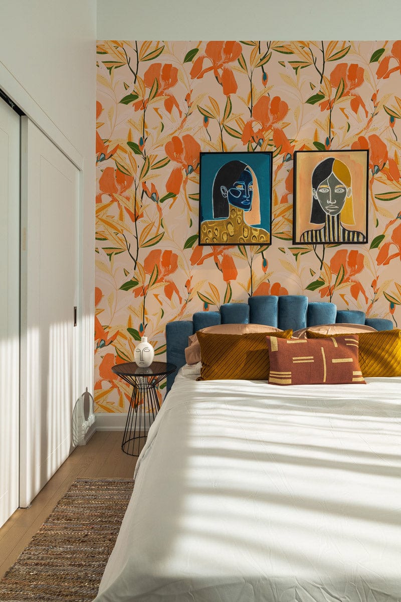 Vibrant orange floral wallpaper in bedroom with blue headboard, colourful pillows, and abstract wall art.