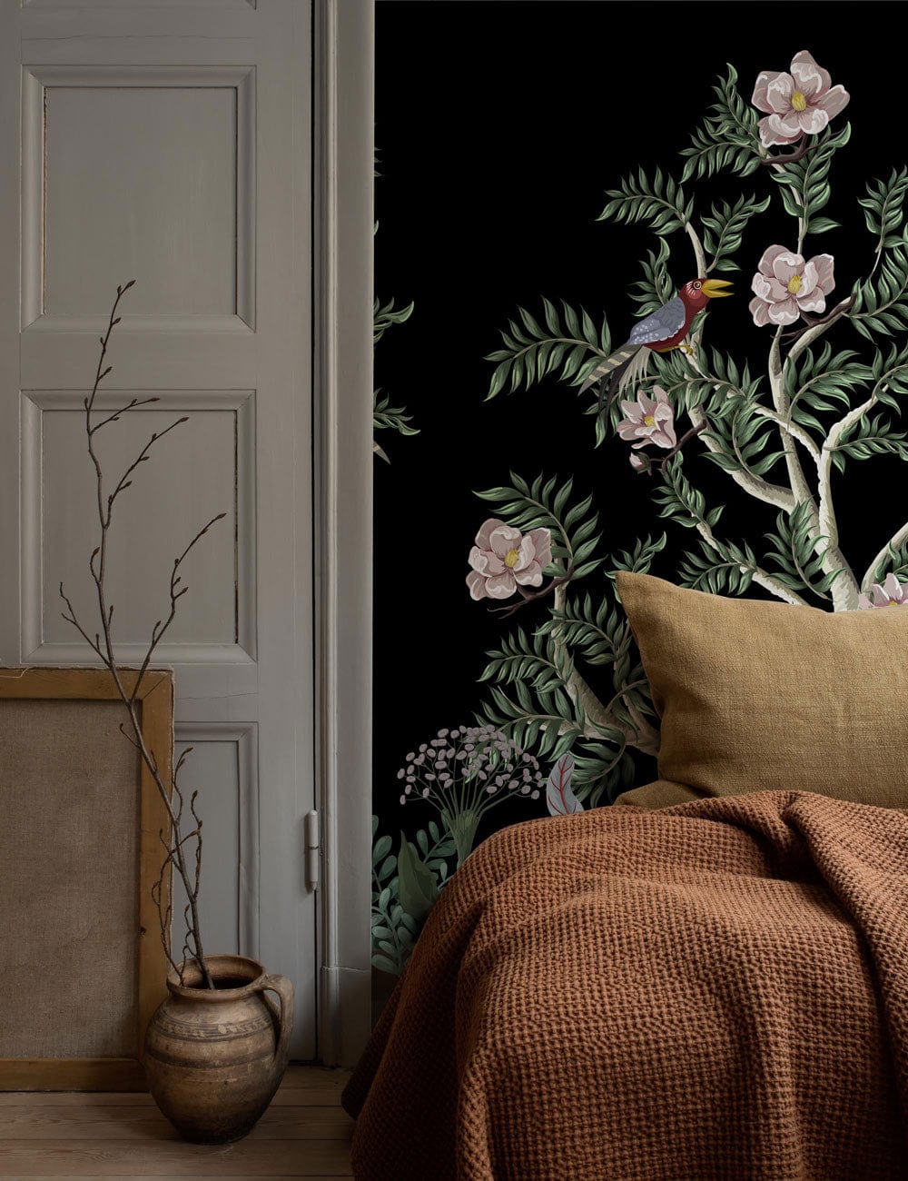 Elegant black garden mural wallpaper with floral-bird design, taupe bedding, rustic wooden flooring.