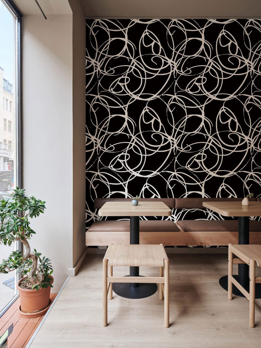 Intricate Art Nouveau floral wallpaper in cafe with light wood tables, beige walls, and plants.