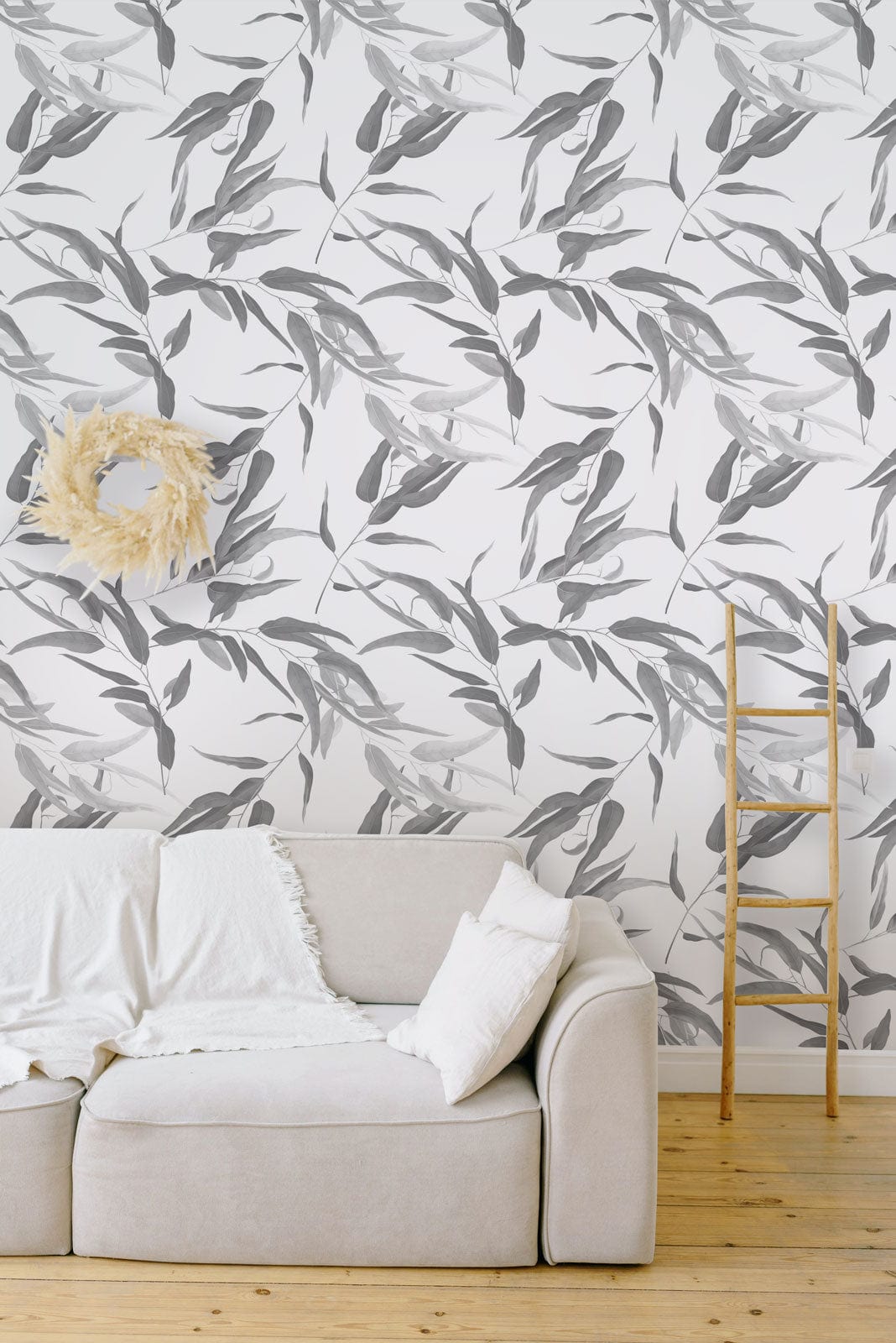 Elegant grey botanical leaf wallpaper, minimalist style, with beige sofa, wooden floor, ladder decor.