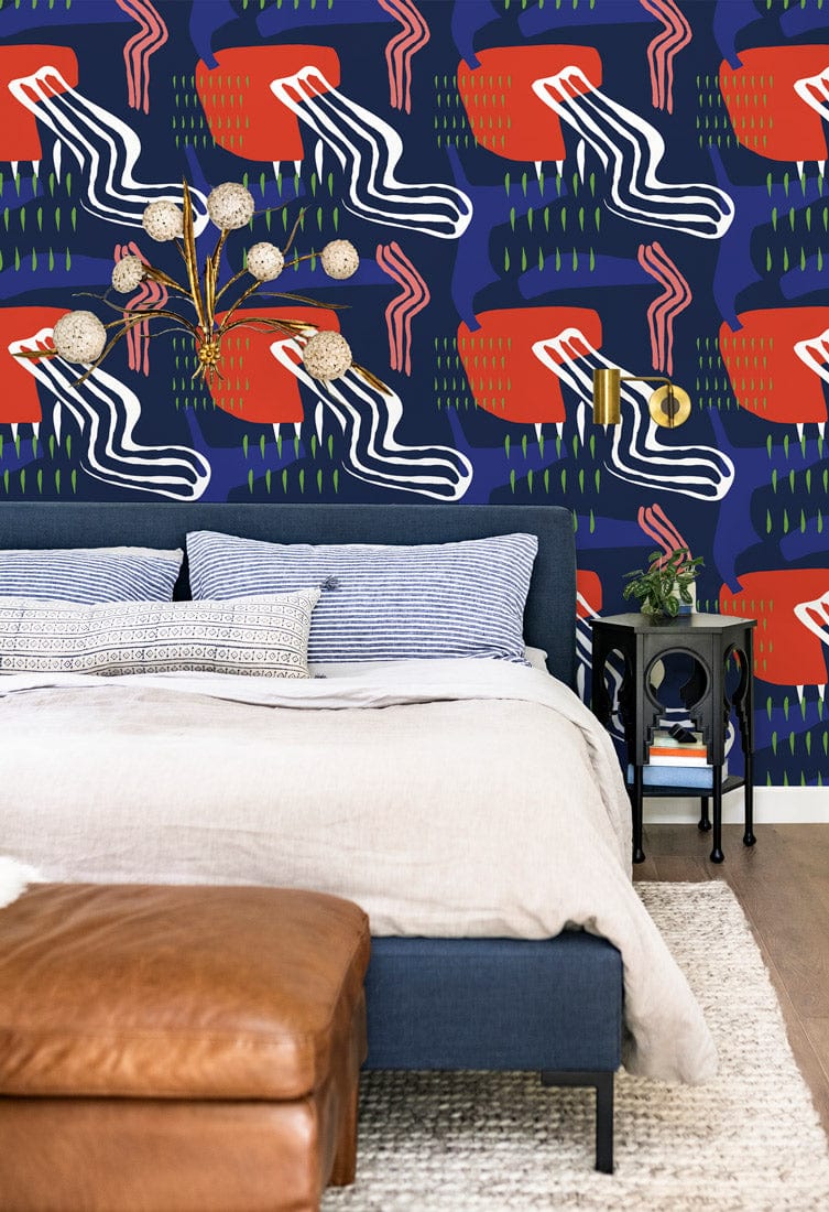 Contemporary abstract navy blue and coral geometric wallpaper in bedroom with blue bed, leather ottoman.