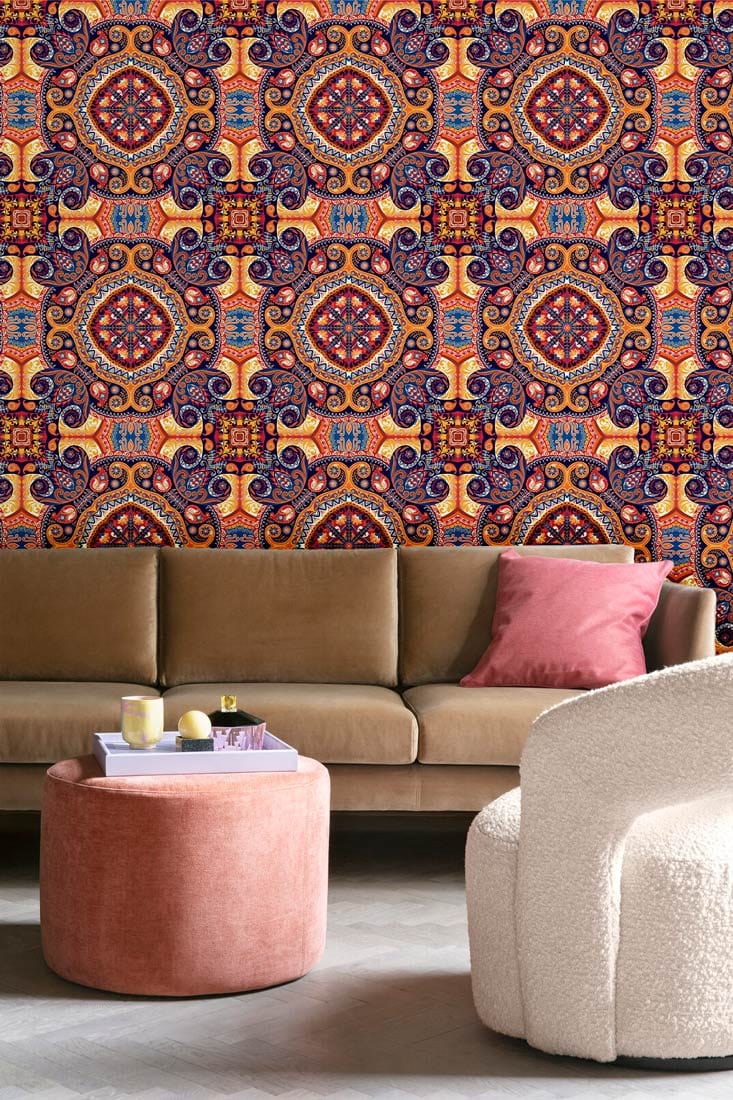 Vintage Bohemian mandala wallpaper; earthy tones; brown sofa; pink cushion; modern neutral armchair; rug flooring.