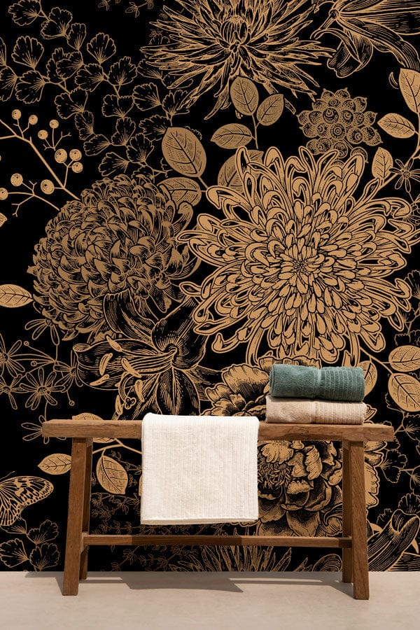 Elegant gold floral botanical wallpaper on black wall, rustic wooden bench, modern indoor setting.