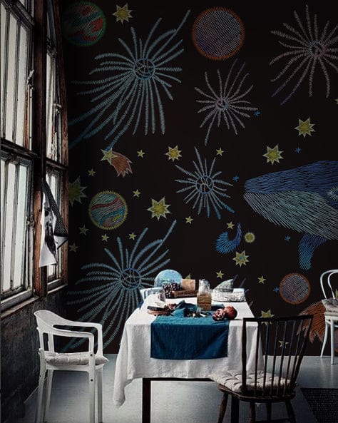 Cosmic Whale mural wallpaper in vibrant multicolour. Dining room with eclectic chairs, rustic windows.