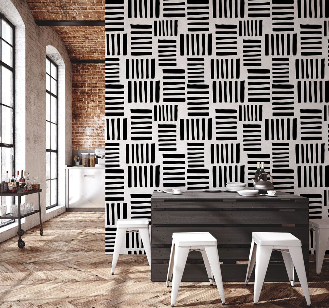 Monochrome geometric stripe wallpaper in dining room with brick wall, wooden flooring, black table, white stools.
