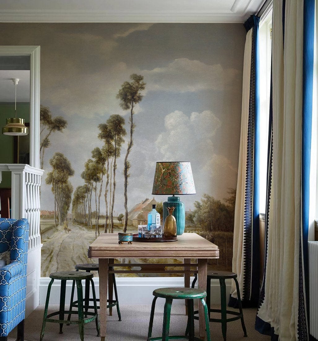 Vintage Countryside Landscape Mural Wallpaper, earthy tones, cosy room, wooden table, blue patterned sofa.