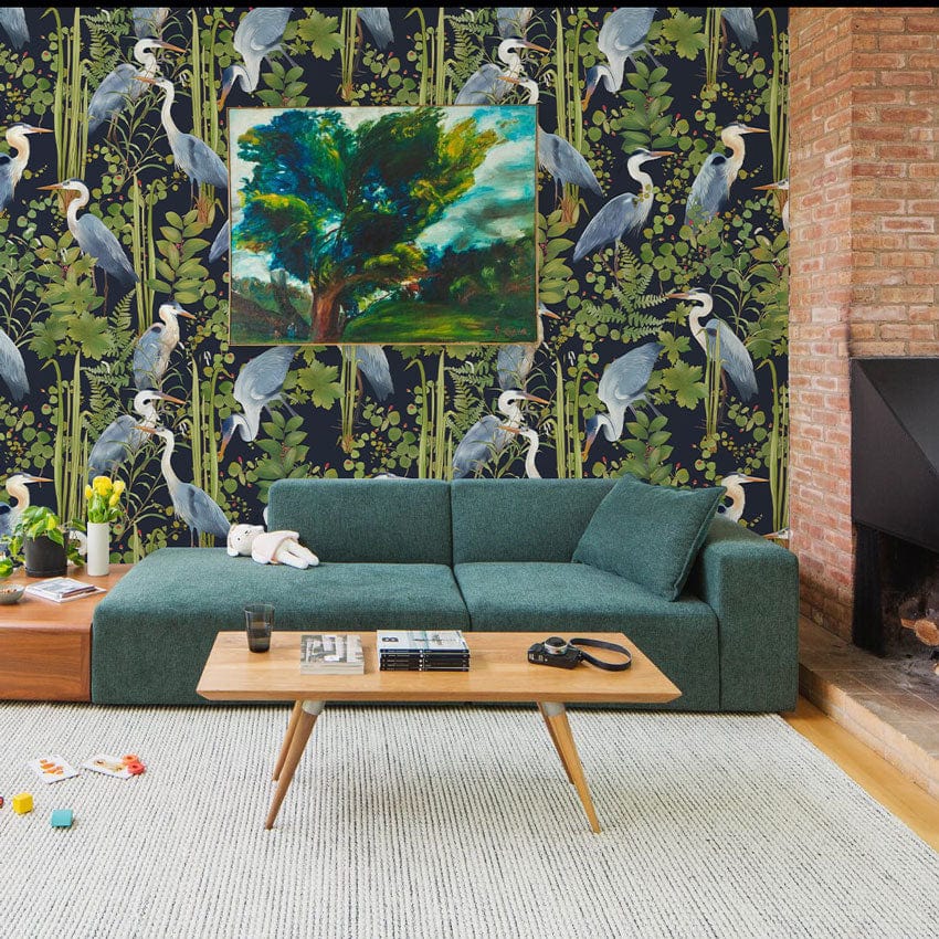 Elegant blue heron wallpaper, green sofa, mid-century table, brick fireplace, wooden flooring, living room.