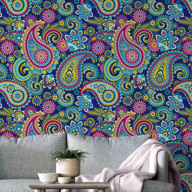 Vibrant paisley wallpaper with colourful floral accents behind grey sofa, bohemian style, living room.