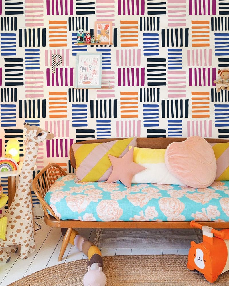 Vibrant wallpaper in geometric stripes, nursery setting with wooden sofa, pastel cushions, white flooring.