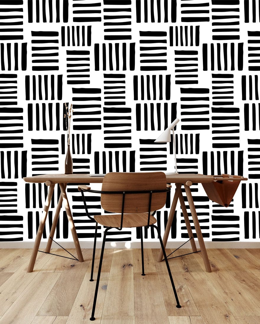 Monochrome geometric stripe wallpaper, wooden desk with lamp, chair, light wood flooring, modern room style.