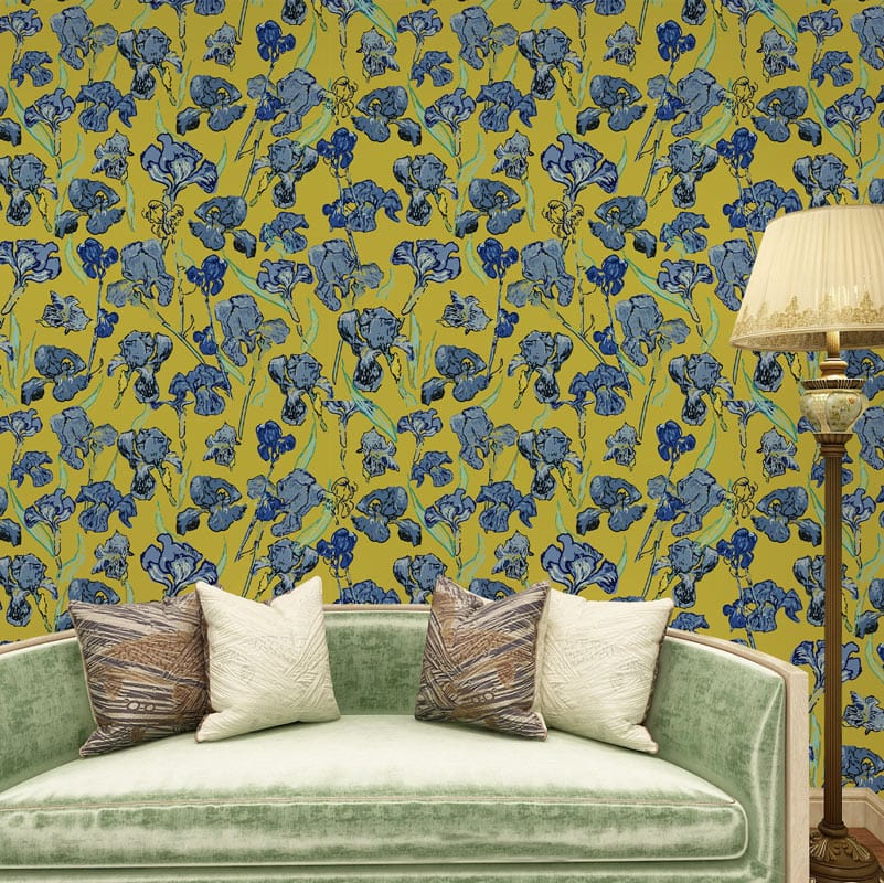 Vintage blue floral wallpaper on mustard, green velvet sofa, elegant beige lamp in living room.