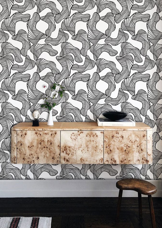 Monochrome abstract line art wallpaper with wooden console, stool, dark flooring in contemporary living room.