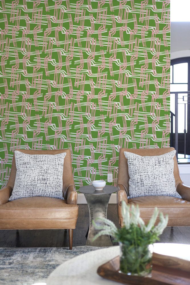 Geometric pink and green wallpaper in modern living room with leather chairs and contemporary decor.