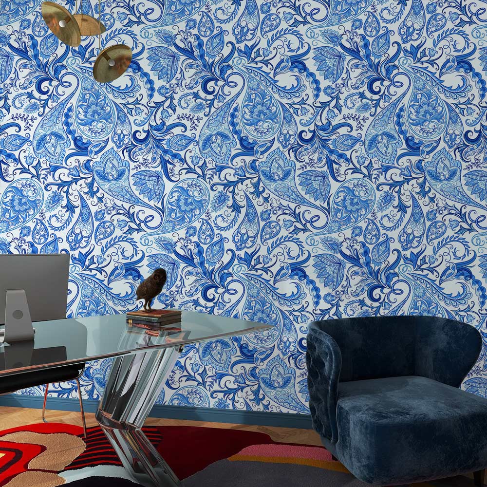Blue floral paisley wallpaper in elegant office with blue velvet chair and modern glass desk.