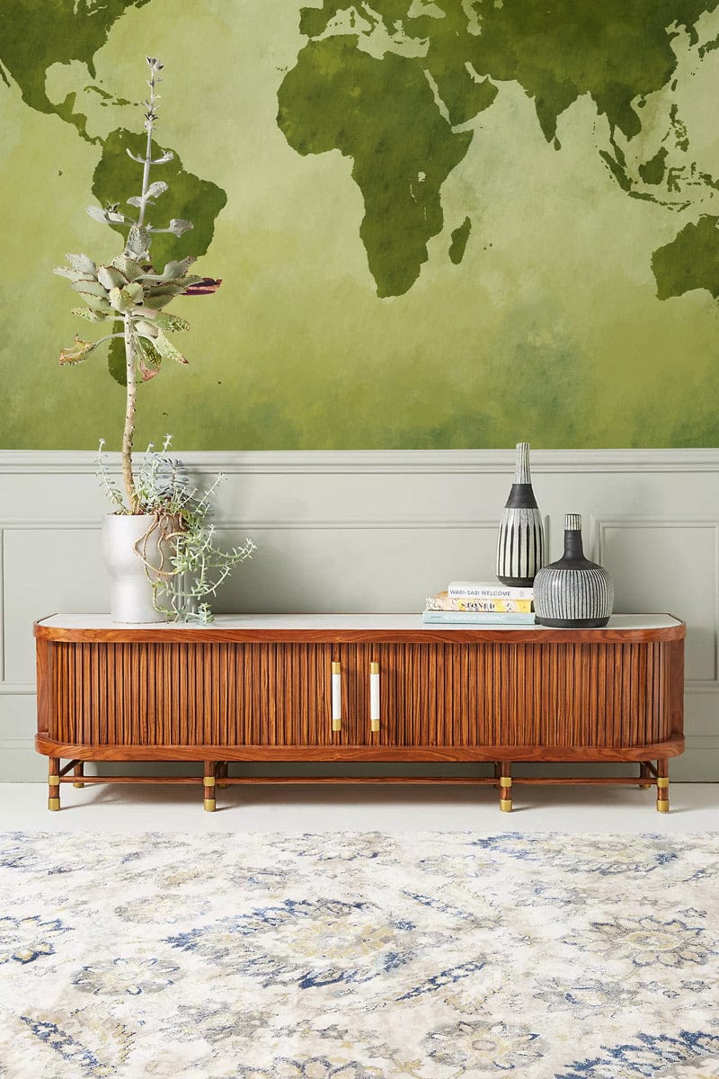 Vintage green world map mural wallpaper in living room, wooden sideboard, light carpet, light wall.