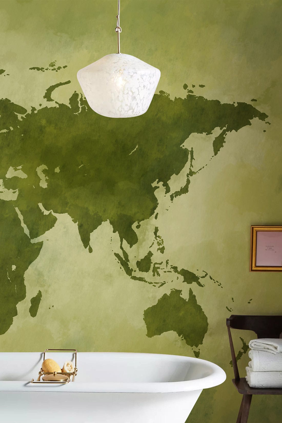 Vintage green world map mural wallpaper in bathroom with white bathtub and modern light pendant.