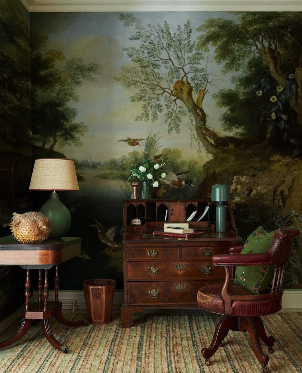 Vintage mural wallpaper with birds, serene lake, antique desk, classic chair, and striped rug flooring.