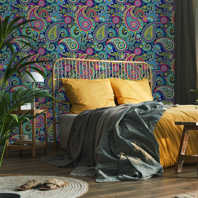 Bohemian room with vibrant paisley wallpaper, mustard cushions on sofa, and modern wooden flooring.