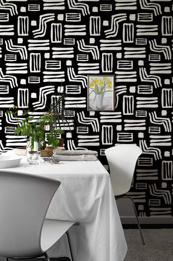 Monochrome geometric tribal wallpaper, black and white, dining room, white chairs, grey carpet, framed art.