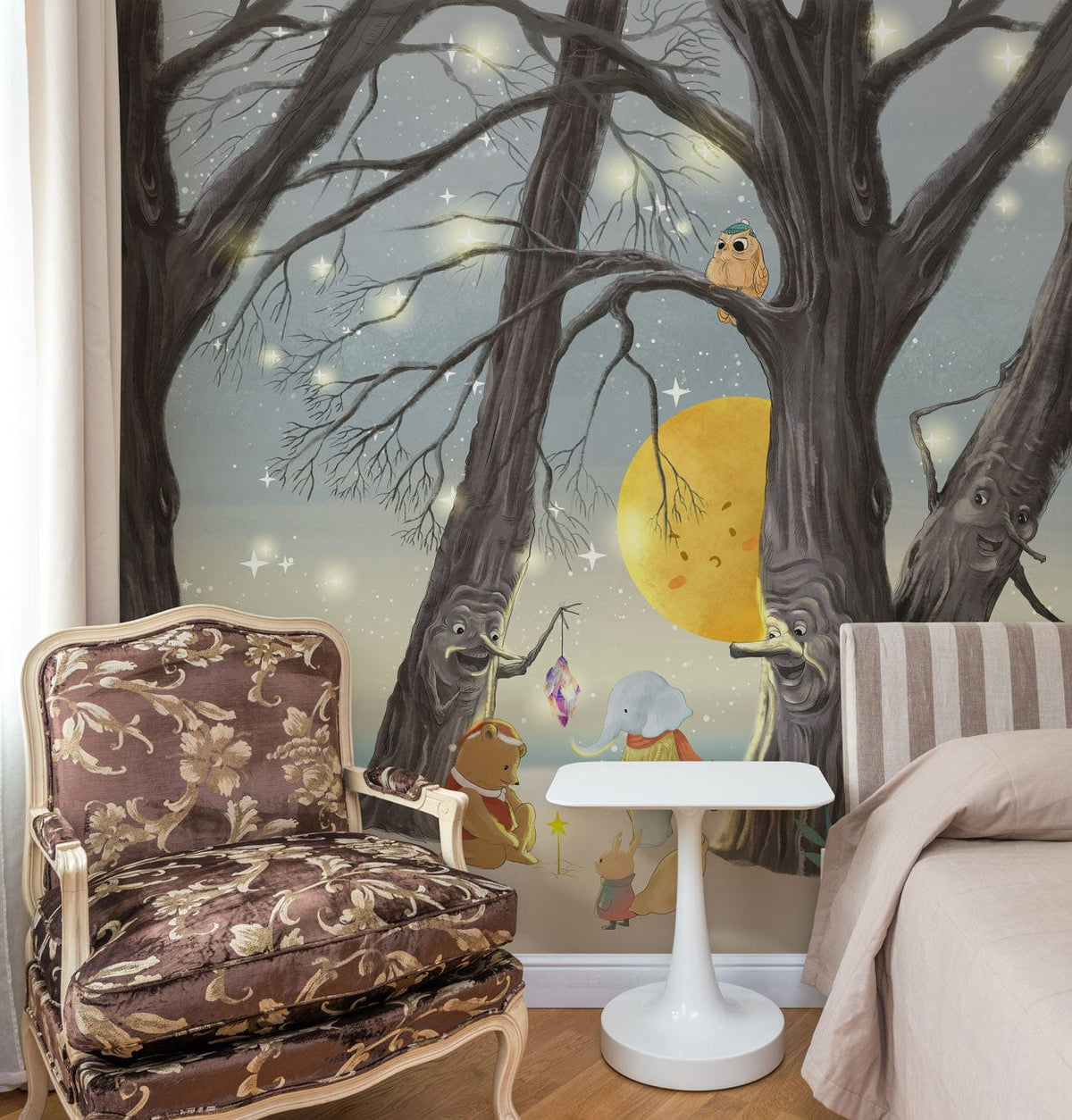 Night sky mural wallpaper with woodland creatures, patterned armchair, white table, striped beige sofa.