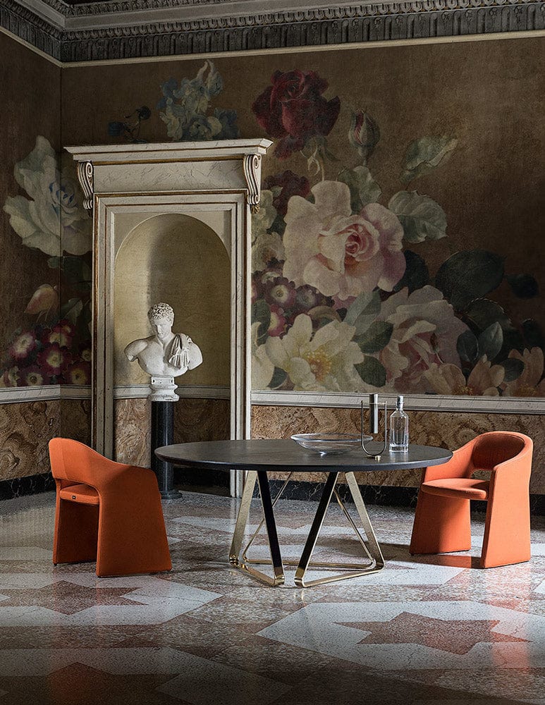 Vintage floral mural wallpaper, earthy tones, elegant round table, orange chairs, marble flooring, classical bust.