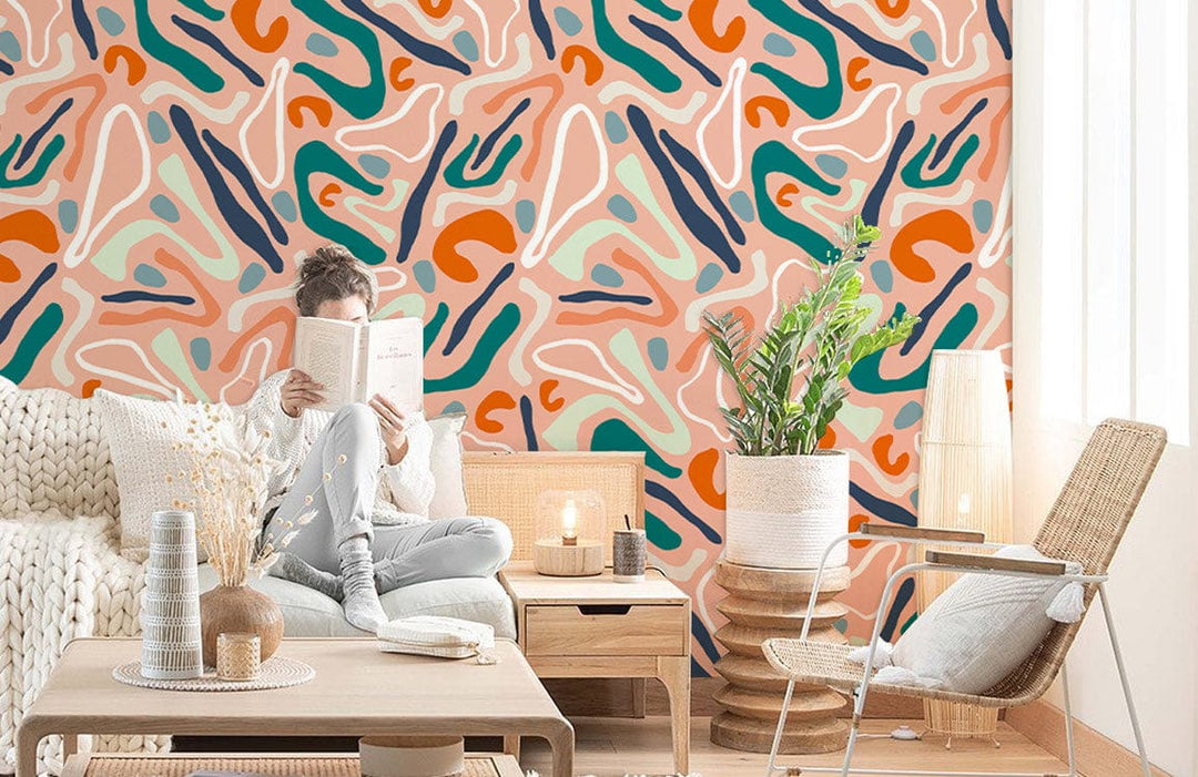 Abstract terracotta and teal wallpaper in cosy living room with beige sofa, wicker chair, wooden table.