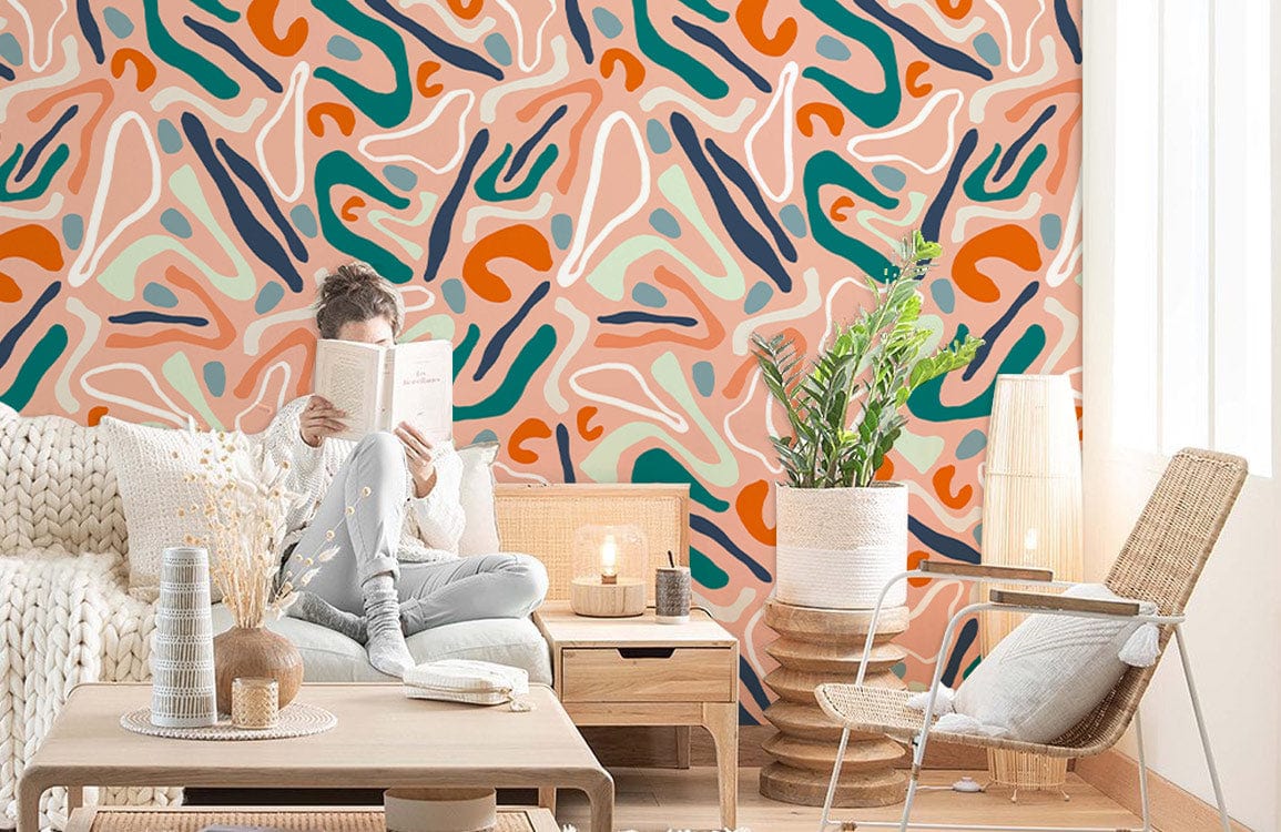 Abstract terracotta and teal wallpaper in cosy living room with beige sofa, wicker chair, wooden table.