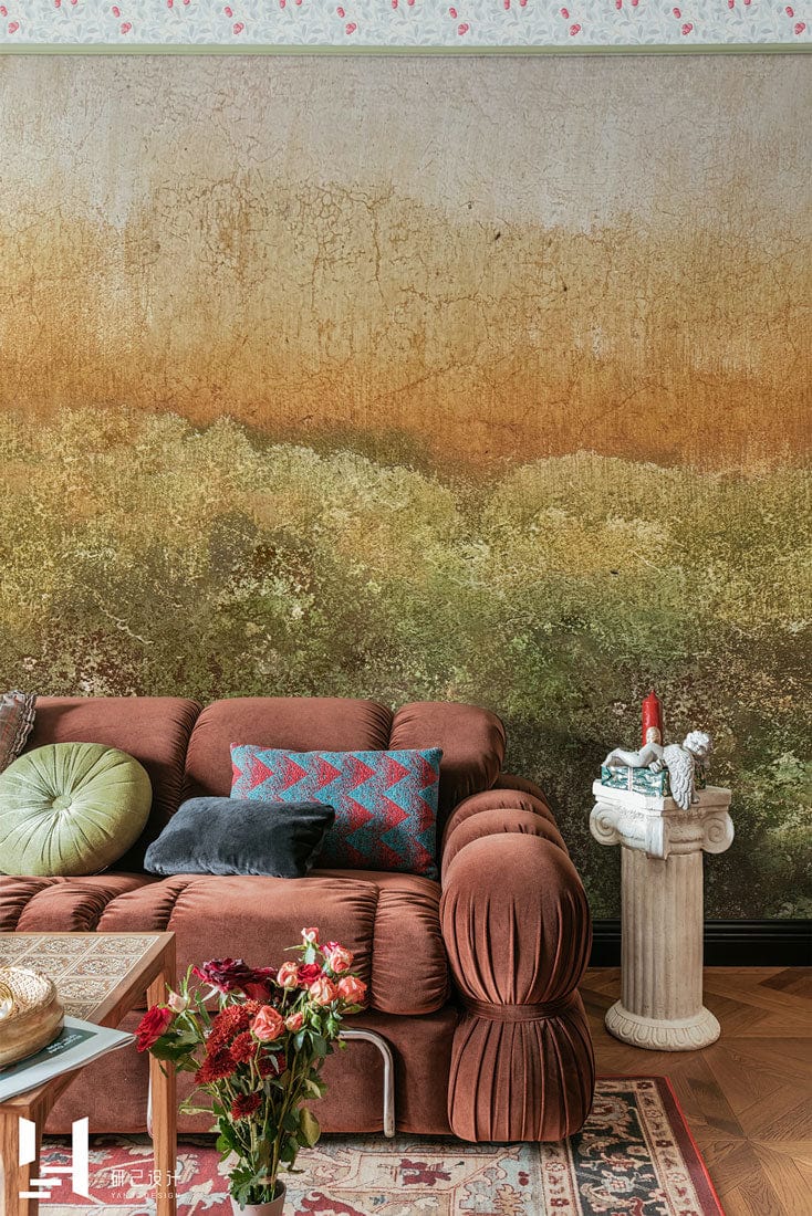 Rustic Autumn Forest mural wallpaper in earthy green, featuring brown sofa, textured wall, and wooden flooring.