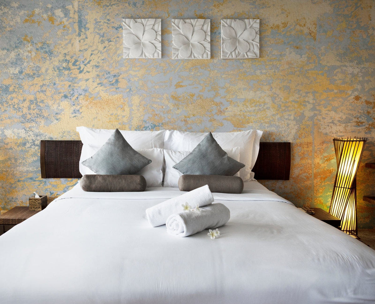 Vintage Pastel Abstract Textured Mural Wallpaper, blue and gold, in bedroom with white bedding and decor.