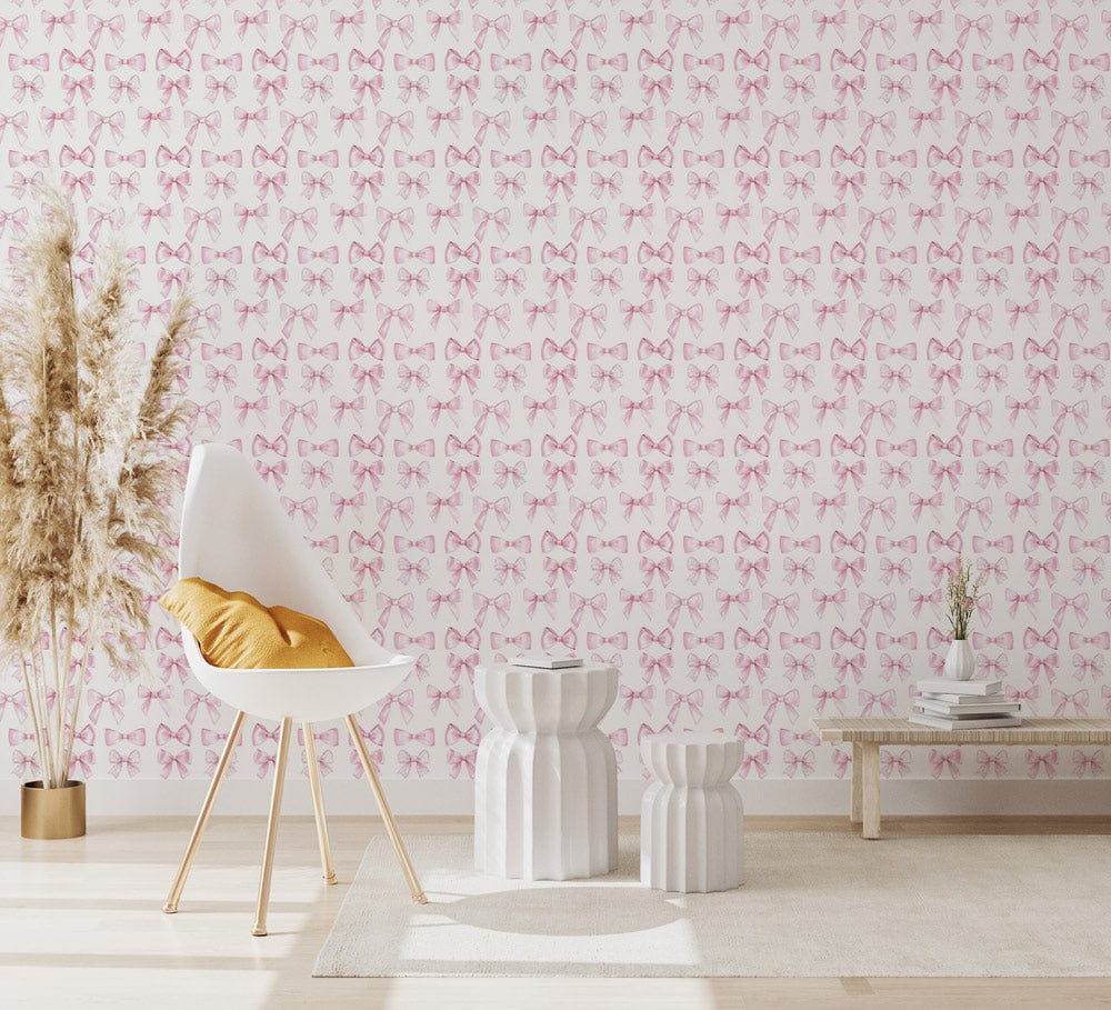 Elegant pink bow wallpaper, white chair, mustard cushion, wooden flooring, stylish neutral room design.
