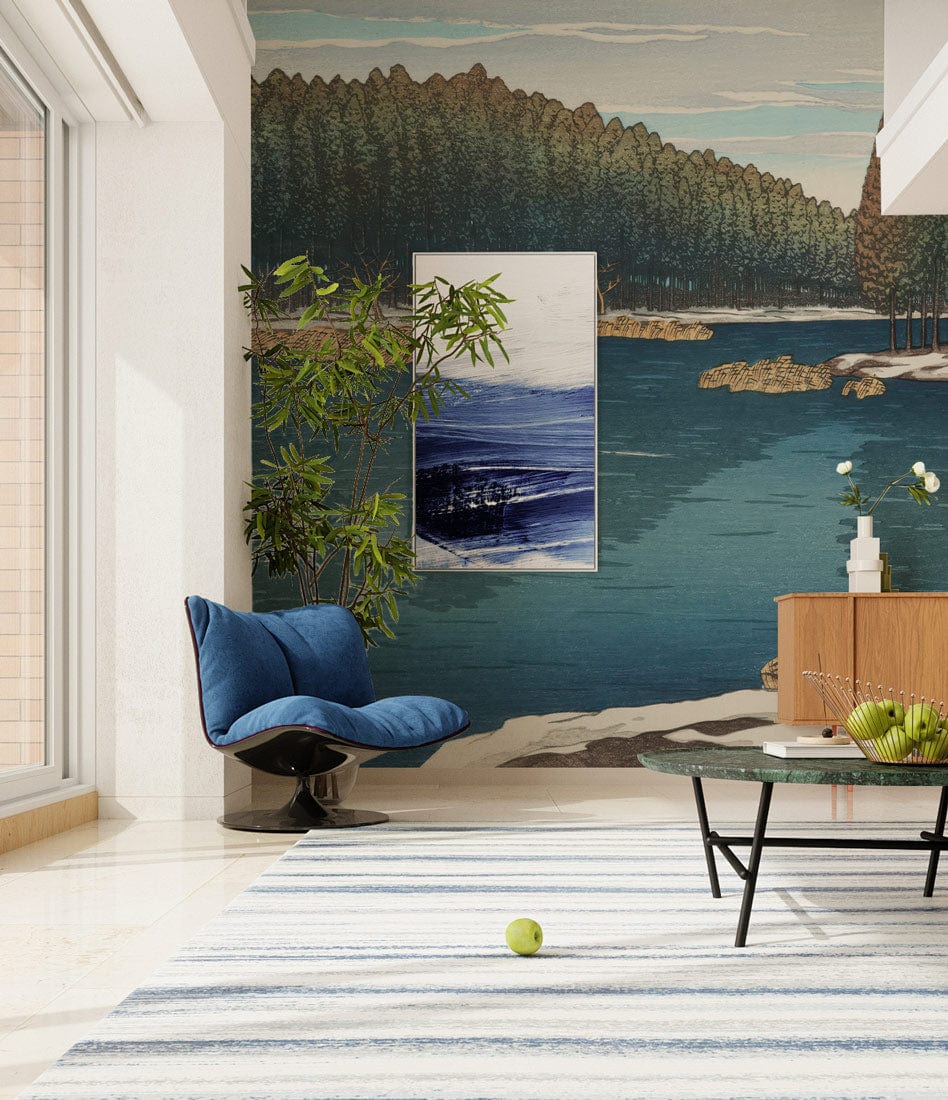 Serene Winter Lake Mural Wallpaper in living room with blue chair, striped rug, and modern cabinet.