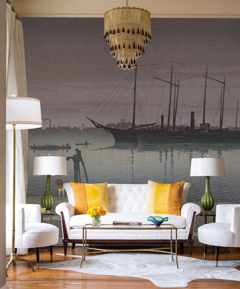 Tranquil Seaside mural with ship and dog scene; white sofa, yellow cushions, chandelier, hardwood flooring.