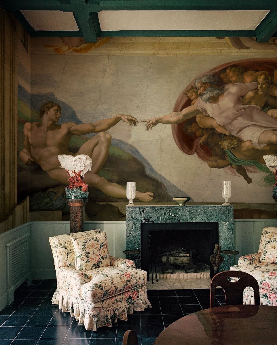 Renaissance Masterpiece Mural Wallpaper in classic living room with floral chairs, marble fireplace, dark flooring.